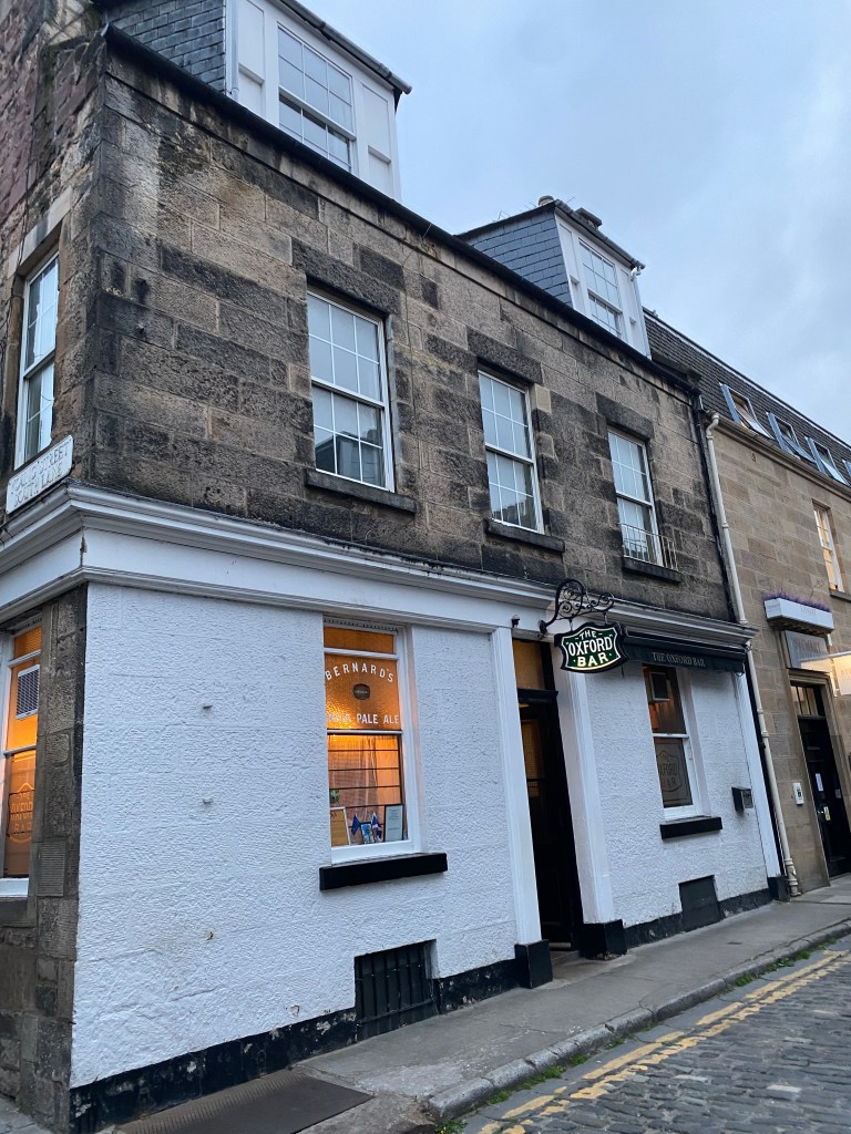 Exterior view of The Oxford Bar, featuring a stone facade, large windows, and a sign above the entrance.